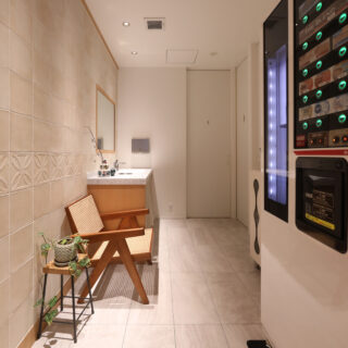 ホワイトとグレーの、清潔感のあるサニタリールームの写真。 洗面台と自動販売機があり、授乳室、トイレに繋がっている。