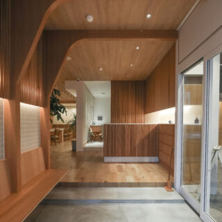 木目調のインテリアで統一されたエントランススペース。 広い土間に、靴の脱ぎ履きのためのベンチが造作されている。 ベンチの上にはmina perhonenのアクセントタイル。